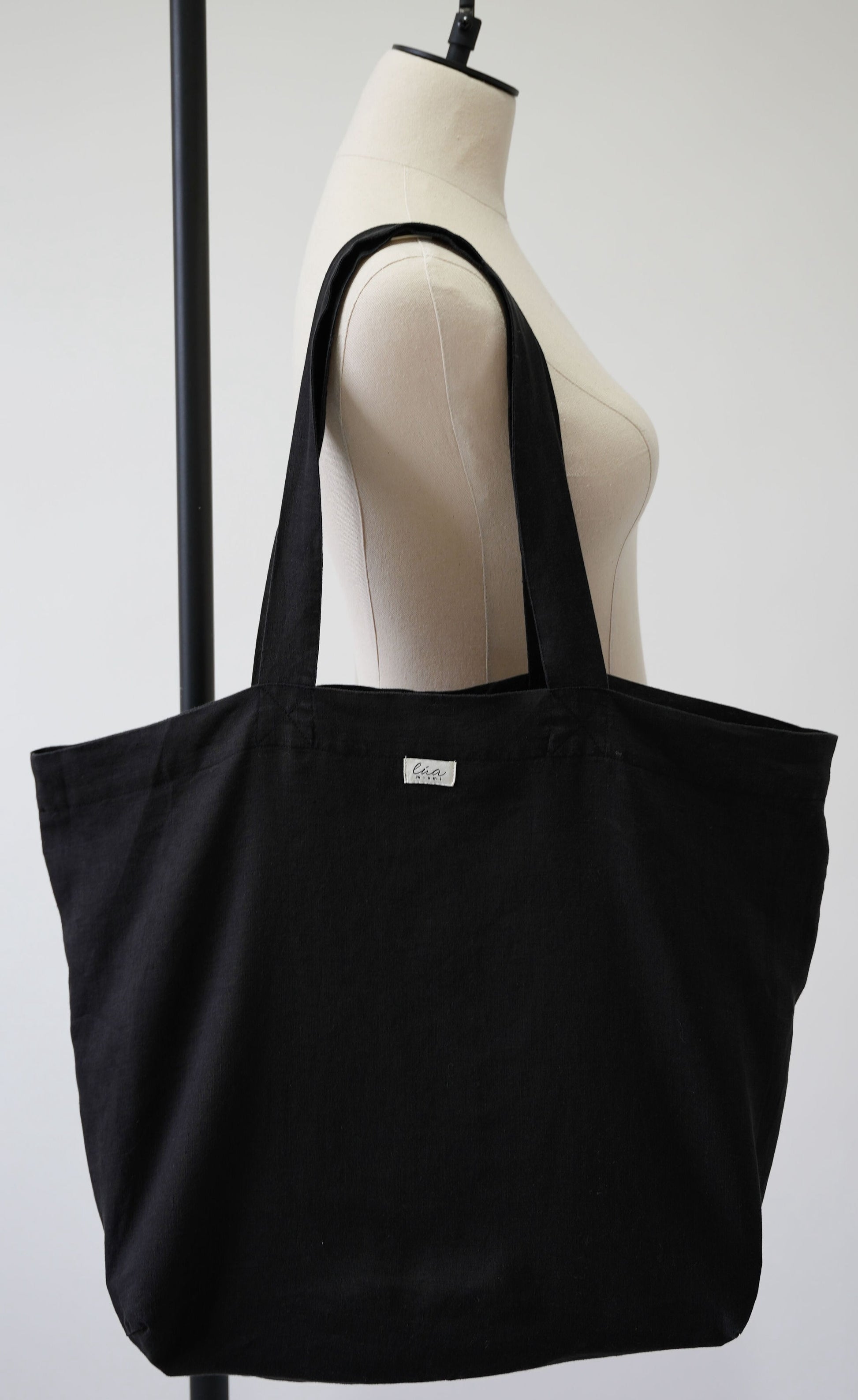 Natural linen tote bag, oversized, black, Lúa Miami logo detail, white studio background — Lúa Miami