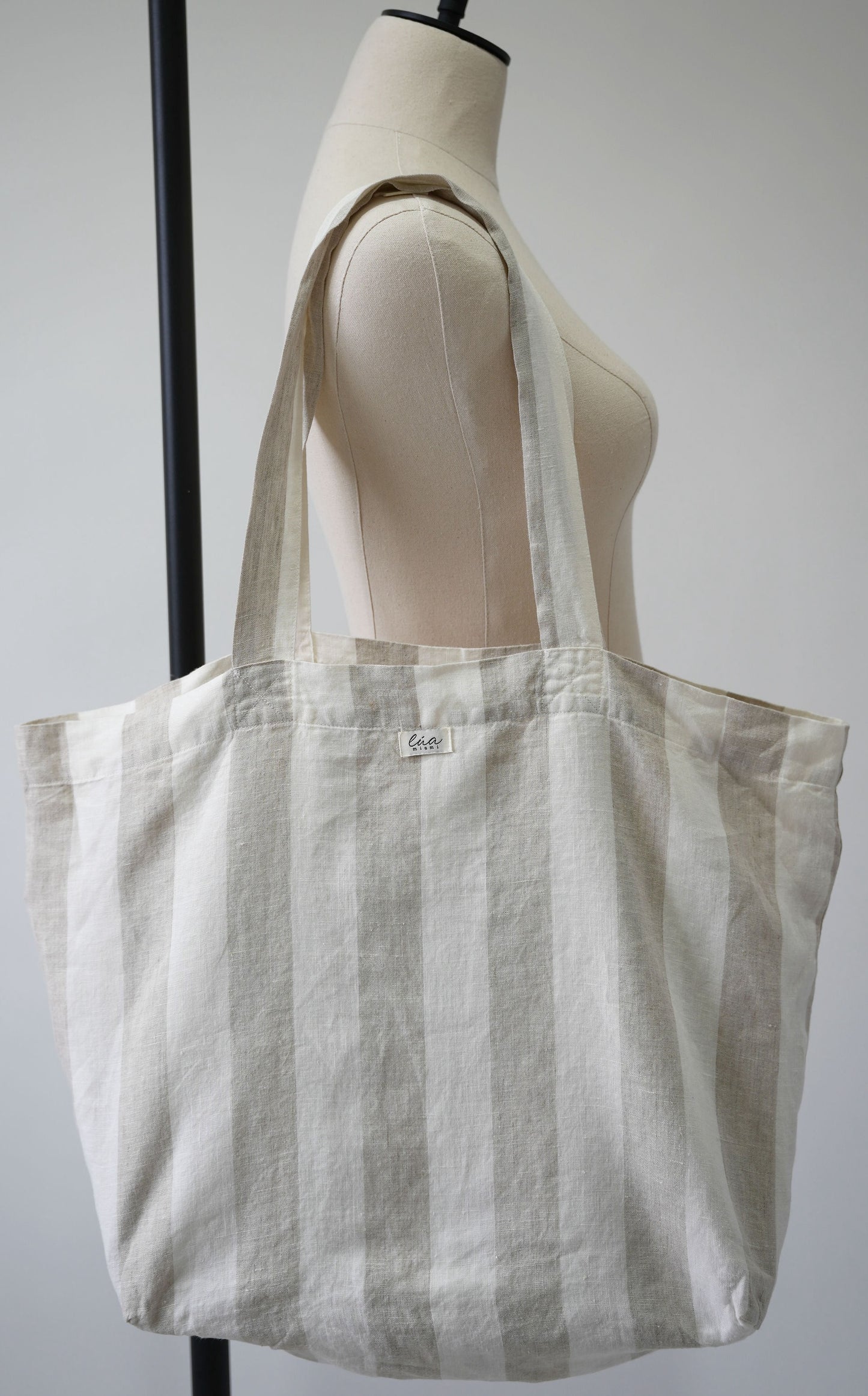 Natural linen tote bag, oversized, soft ivory and white stripes, Lúa Miami logo detail, white studio background — Lúa Miami