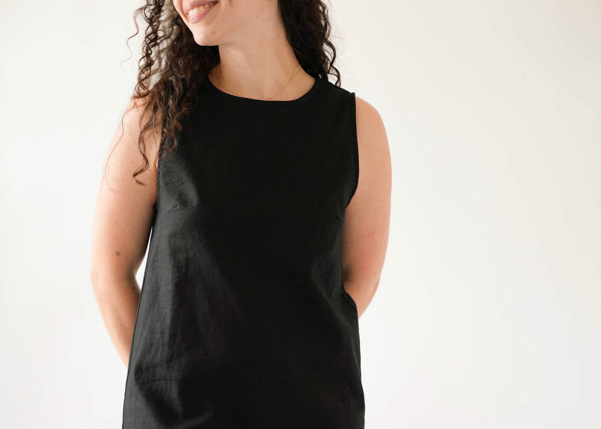 Woman wearing a black sleeveless dress against a white background