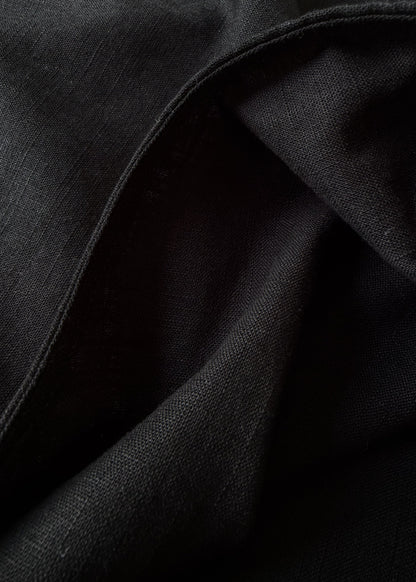 A close-up of draped black fabric with visible woven texture and soft folds.