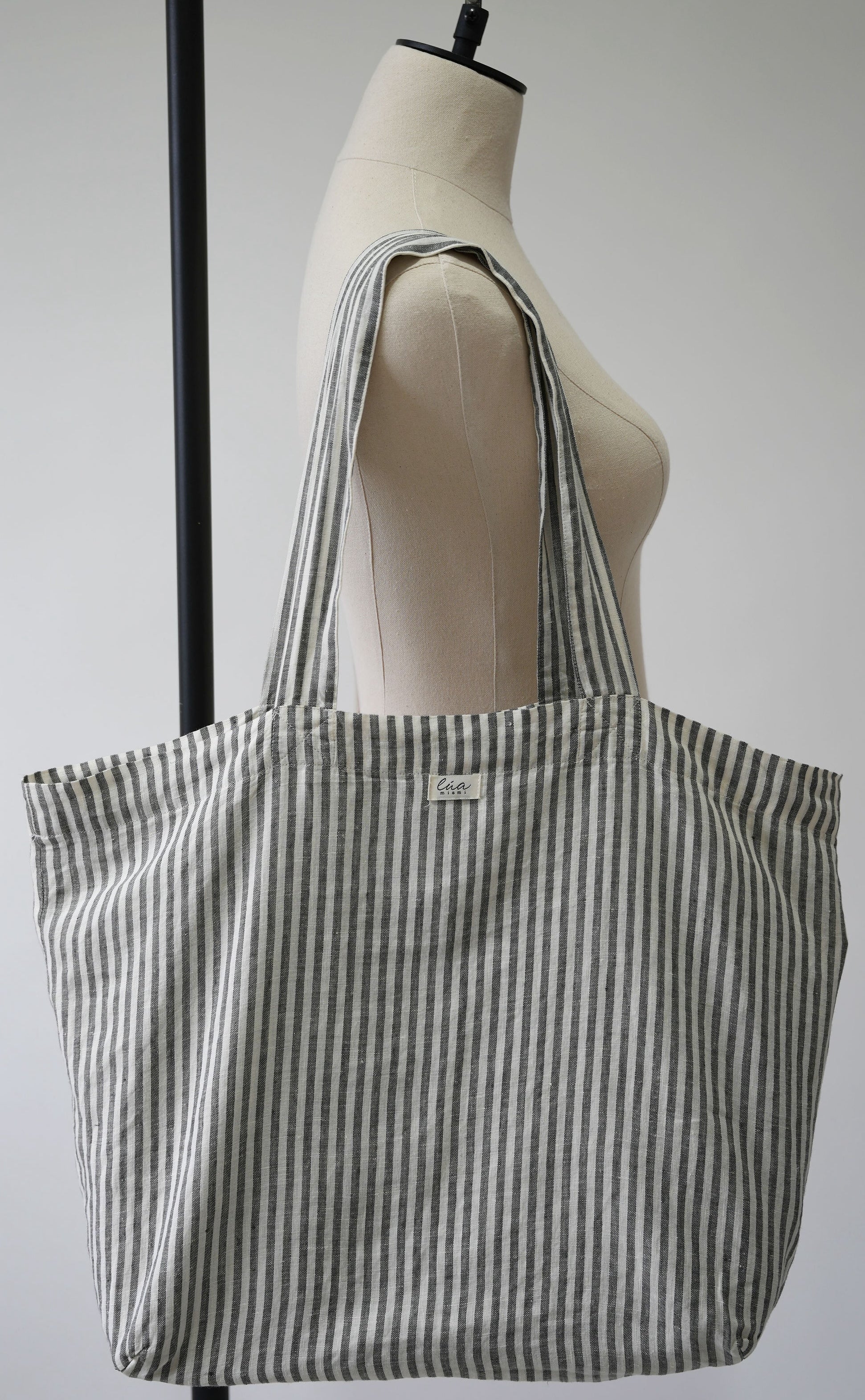 Natural linen tote bag, oversized, white and grey stripes, Lúa Miami logo detail, white studio background — Lúa Miami